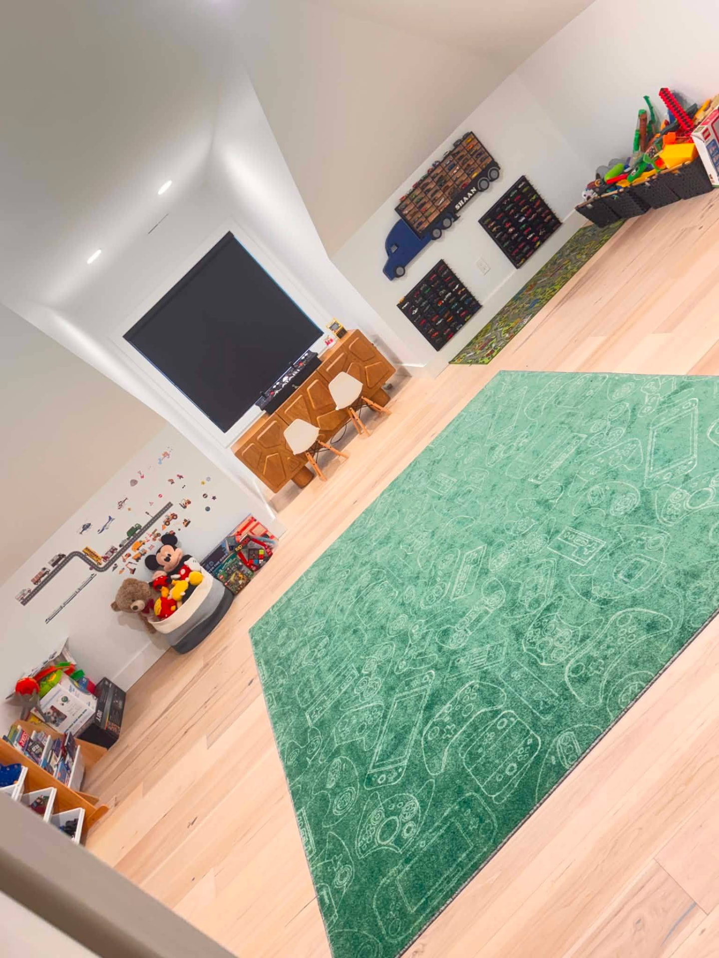 Organized, clean playroom with green rug and light wood floors